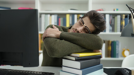 Young hispanic man student sleeping with head on books at library university