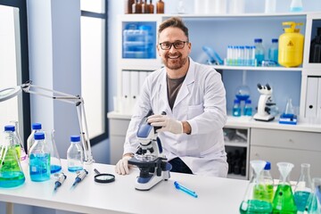 Middle age caucasian man working at scientist laboratory looking positive and happy standing and...