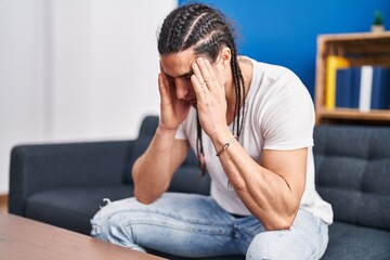 Young man sitting on sofa with worried expression at home