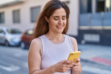 Young woman smiling confident using smartphone at street