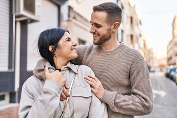 Man and woman couple smiling confident hugging each other standing at street