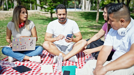 Group of people students using laptop and smartphone studying at park