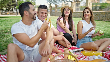 Group of people having healthy picnic sitting on grass at park