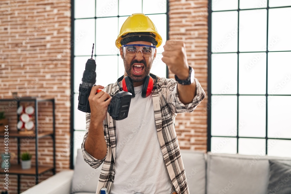 Sticker young hispanic man with beard working at home renovation annoyed and frustrated shouting with anger,