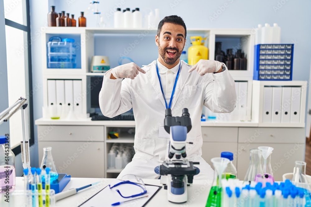 Sticker young hispanic man with beard working at scientist laboratory looking confident with smile on face, 