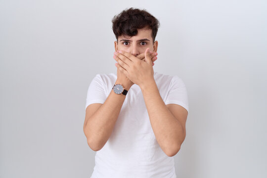 Young non binary man wearing casual white t shirt shocked covering mouth with hands for mistake. secret concept.