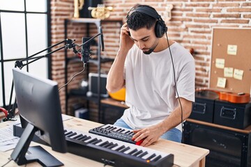 Young arab man musician playing piano keyboard at music studio