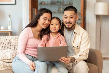 Young asian father, mother and daughter using computer at home