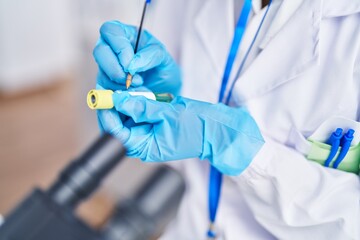 Young african american woman scientist writing on test tube at laboratory