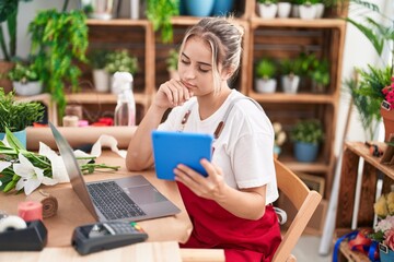 Young blonde woman florist using laptop and touchpad at flower shop