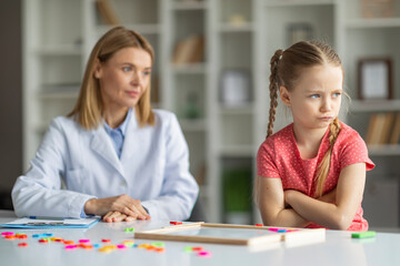 Kids mental health. Offended girl sitting with folded arms at psychologist office