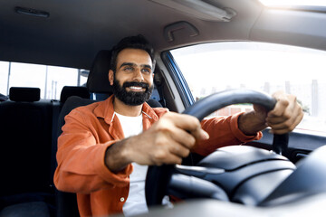 Happy middle eastern man sitting in vehicle, driving new auto
