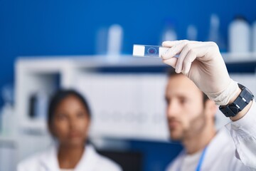 Man and woman scientists holding sample working at laboratory