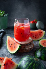 Slices of watermelon, blueberries and strawberries and watermelon smoothie on grey blue background 