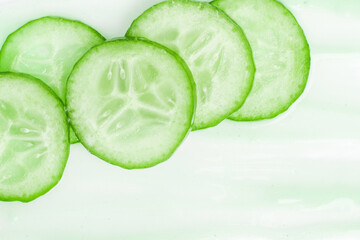 Slides of fresh cucumber on a cream smear. On a white background.
