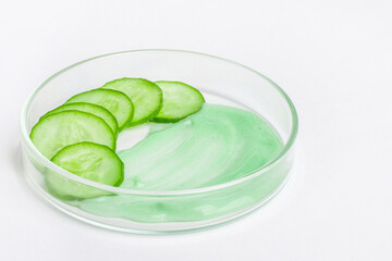 Thinly sliced slices of fresh green cucumber in a Petri dish. A smeared smear of green cucumber cream.