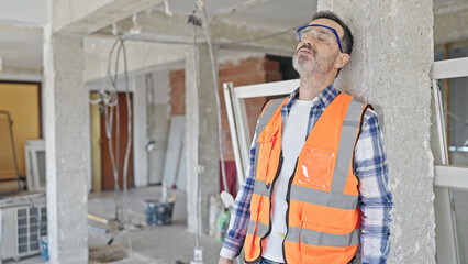 Middle age man builder tired taking out hardhat at construction site