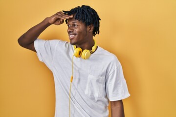 Young african man with dreadlocks standing over yellow background very happy and smiling looking...