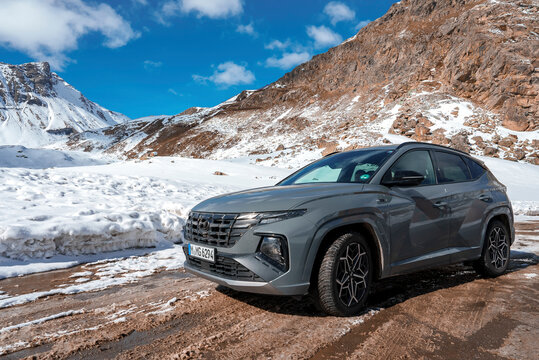 Brand new Hyndai Tucson 2023 SUV car parked by the side of the road with mountain range and clear sky in background in Switzerland.