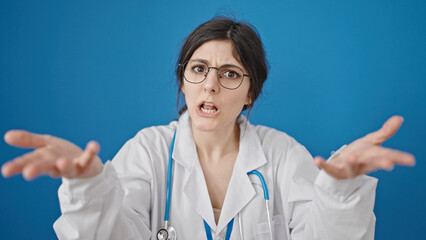 Young beautiful hispanic woman doctor angry and stressed over isolated blue background