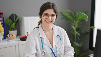 Young beautiful hispanic woman doctor using computer working at clinic