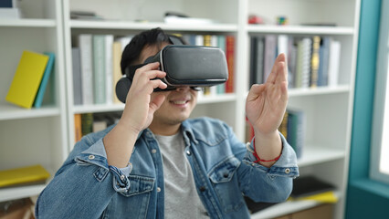 Young chinese man student smiling confident using virtual reality glasses at library university