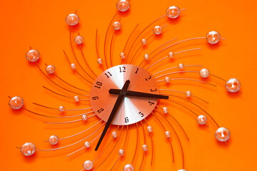 clock on orange wall , closeup