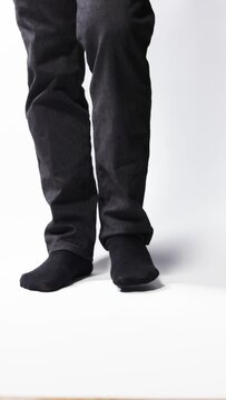 Legs of a man demonstrating black socks on a white background