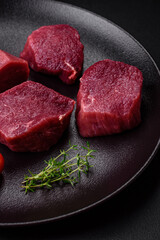 Juicy raw beef with spices, salt and herbs on a dark concrete background