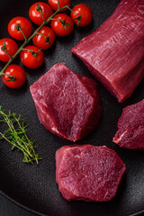 Juicy raw beef with spices, salt and herbs on a dark concrete background