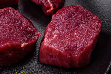 Juicy raw beef with spices, salt and herbs on a dark concrete background