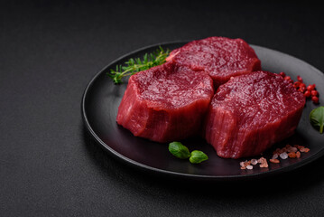 Juicy raw beef with spices, salt and herbs on a dark concrete background