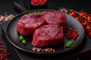 Juicy raw beef with spices, salt and herbs on a dark concrete background