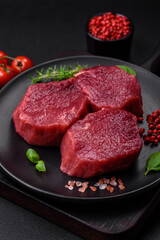 Juicy raw beef with spices, salt and herbs on a dark concrete background