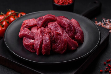 Juicy raw beef with spices, salt and herbs on a dark concrete background