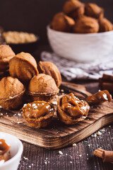 Homemade walnut shaped cookies filled with boiled condensed milk on a board vertical view