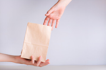 Hand giving a disposable zero waste paper bag to another hand