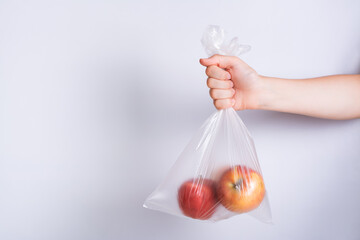 Hand holding a disposable transparent bag with apples