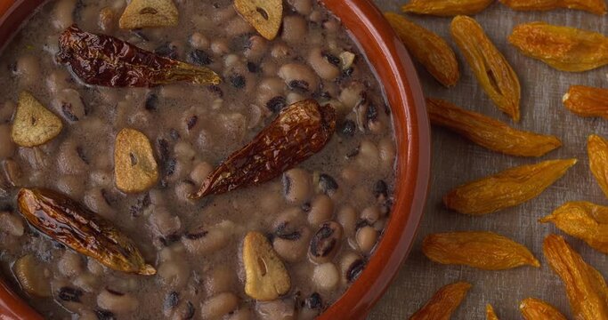 Frijoles Refritos. Refried beans with fried garlic and chili on coconut oil. Dried chilies on the table.  