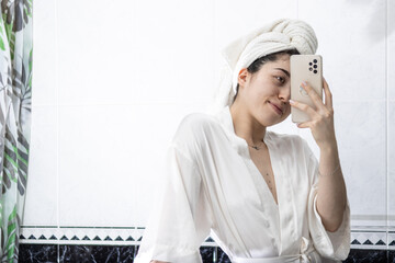 Photo of a woman taking a selfie while wearing a towel on her head