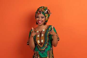 Funny positive black woman pointing at camera on orange