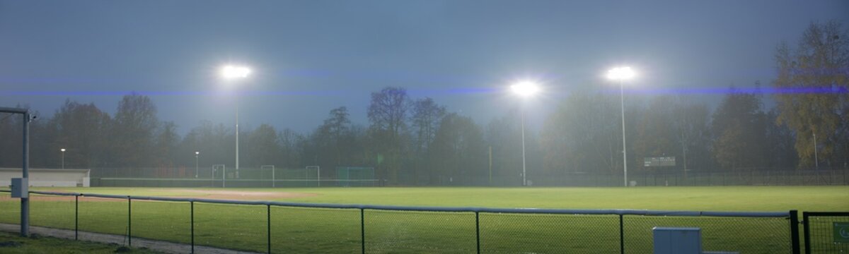 WIDE view of empty baseball field at dusk under heavy rain. Stadium flood lights are turned on. Shot with 2x anamorphic lens