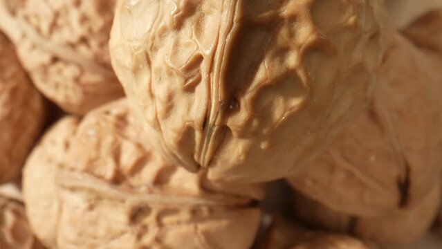 Macro video showcases the intricate patterns and textures of walnuts, revealing their rich brown hues and unique shell formations. Grain and food concept. Walnuts background. 4K HDR
