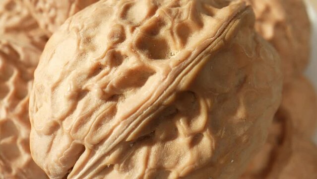 Macro video showcases the intricate patterns and textures of walnuts, revealing their rich brown hues and unique shell formations. Grain and food concept. Walnuts background. 4K HDR

