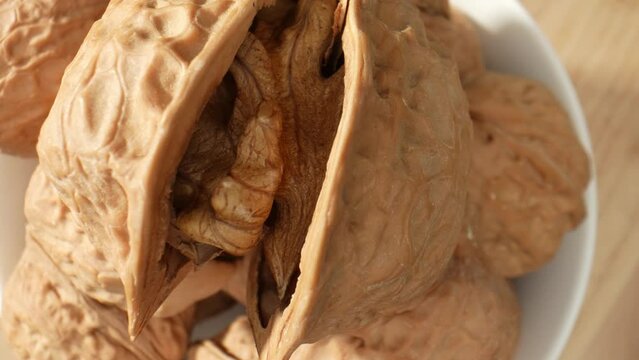 The video captures the intricate patterns of the walnut's halves. The convoluted folds and grooves create a mesmerizing sight, resembling a miniature landscape. Food concepts. Walnuts background. 4K
