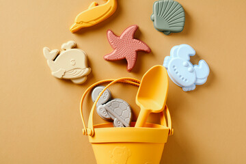 Silicone beach toys, bucket, shovel on sand color background.
