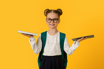 Study And Technologies. Smiling Little Schoolgirl Holding Paper Book And Digital Tablet