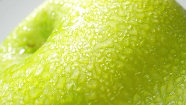 Experience the captivating beauty of a green apple like never before through a mesmerizing A green apple with droplets of water. macro video.
