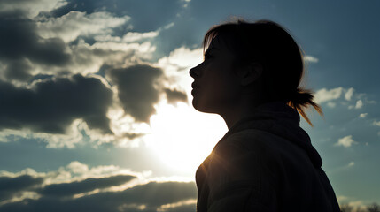 Silhouette of a tired and stressed woman against the sky, sun