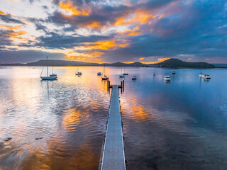 Aerial sunrise over the water with low cloud cover, boats and reflections